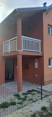 a red building with a balcony and a fence at Apartmani Donji Vakuf in Donji Vakuf