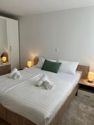a bedroom with a large white bed with towels on it at Apartmani Pervan in Livno