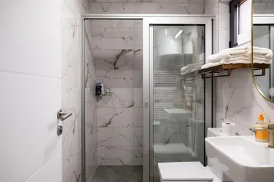 a white bathroom with a shower and a sink at Kraljičini konaci in Doboj