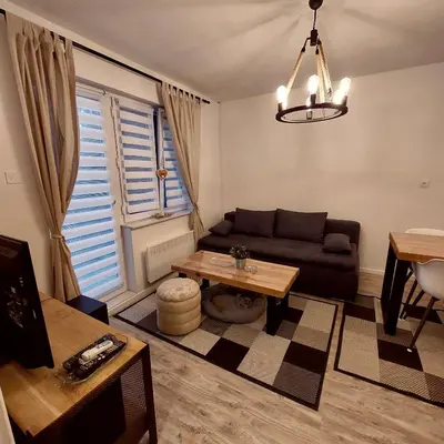a living room with a couch and a table at Vikendica Niki - Village house with pool in Ćetojevići