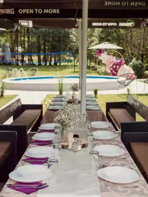 a long table with white plates and purple napkins at Vikendica Niki - Village house with pool in Ćetojevići