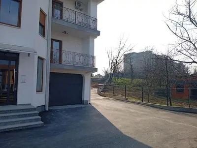 a white house with a garage and a fence at Apartman Nera in Gradačac