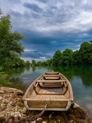 a wooden boat chained to the shore of a river at UNA Escape in Glodina