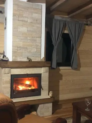 a fireplace in a log cabin with a fire in it at Log Cabin Plavšić - Vikendica Plavšić in Šipovo