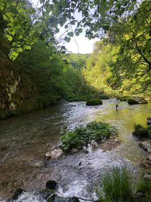 a river with a person standing in the water at Log Cabin Plavšić - Vikendica Plavšić in Šipovo