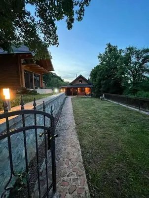 a fence in front of a house with a building at Log Cabin Plavšić - Vikendica Plavšić in Šipovo
