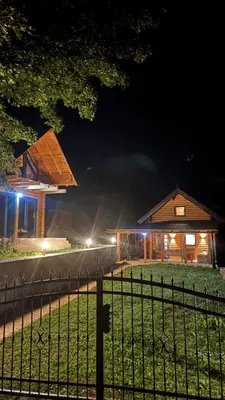 a wooden house at night with a fence at Log Cabin Plavšić - Vikendica Plavšić in Šipovo