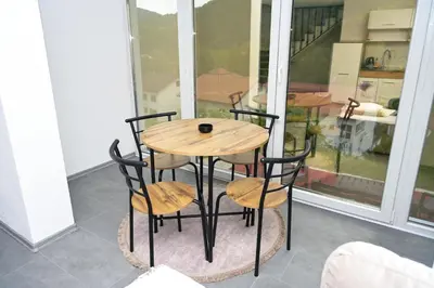 a wooden table and four chairs on a balcony at Ćato s cottage in Bravnice