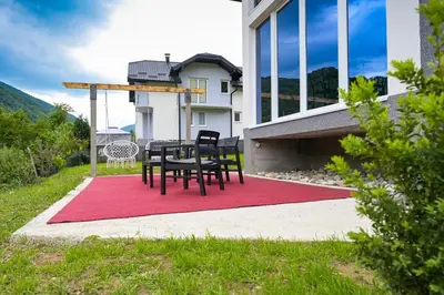 a table and chairs on a red rug in front of a house at Ćato s cottage in Bravnice