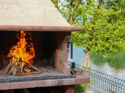 a brick oven with fire in it next to a lake at Ranch Una Soul in Glodina