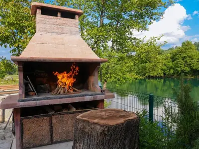 a brick oven with a fire in it next to a lake at Ranch Una Soul in Glodina