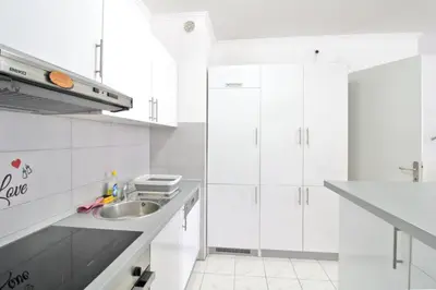a white kitchen with white cabinets and a sink at Apartman Slani San in Tuzla