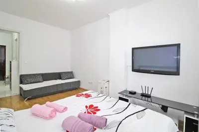 a bedroom with a bed with pink pillows and a flat screen tv at Apartman Slani San in Tuzla
