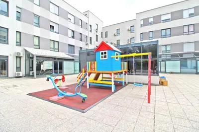 a playground in a courtyard with a building at Apartman Slani San in Tuzla