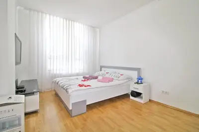 a white bedroom with a bed with red flowers on it at Apartman Slani San in Tuzla