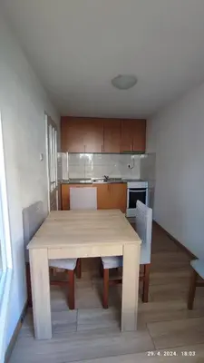 a dining room table with chairs and a kitchen at Apartmani Elix II in Ivišovo Greblje
