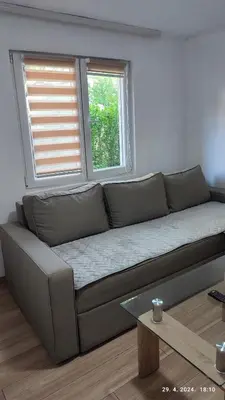 a couch in a living room with two windows at Apartmani Elix II in Ivišovo Greblje