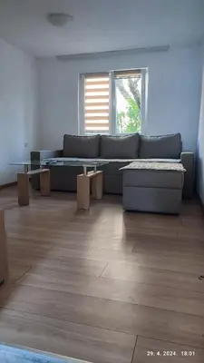 a living room with a blue couch and a window at Apartmani Elix II in Ivišovo Greblje