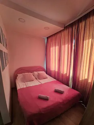 a small bedroom with a red bed with two pillows at Apartman Annie in Bihać