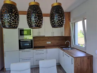 a kitchen with white cabinets and two lights at Villa Vienna in Bužim