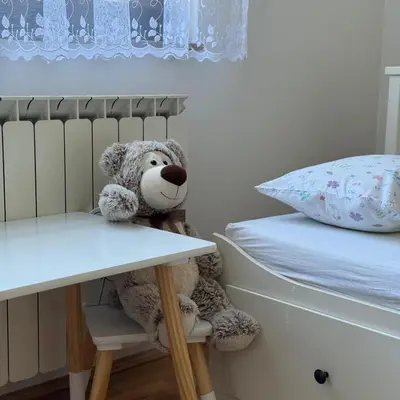 a teddy bear sitting in a chair next to a bed at Apartman Dar in Bihać