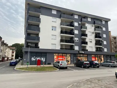 a large building with cars parked in a parking lot at Apartman VIP in Modriča