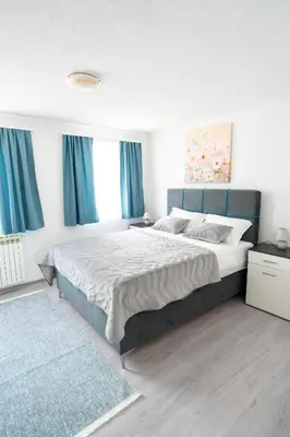 a bedroom with a large bed with blue curtains at Apartman 11 in Tomislavgrad