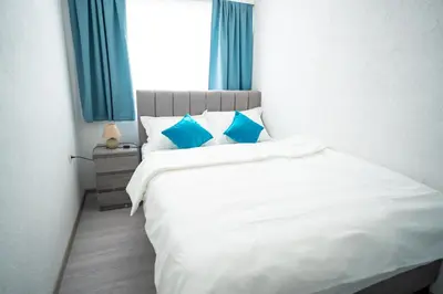 a white bed with blue pillows in a bedroom at Apartman 11 in Tomislavgrad