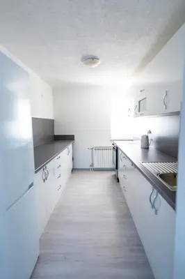 a kitchen with white cabinets and a wooden floor at Apartman 11 in Tomislavgrad