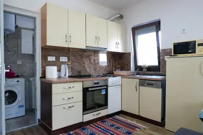 a kitchen with white cabinets and a washer and dryer at Villa Plavno in Otoka