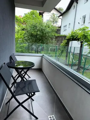 a balcony with a table and a chair and a window at Stan Tesanj in Tešanj