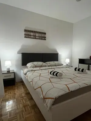a white bedroom with a large bed with two lamps at Apartman Filip in Jajce