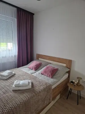 a bedroom with a bed with pink pillows and a window at Apartman Eden in Doboj