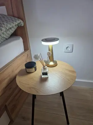 a table with a lamp on it next to a bed at Apartman Eden in Doboj
