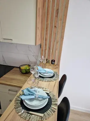 a wooden table with plates and glasses on it at Apartman Eden in Doboj