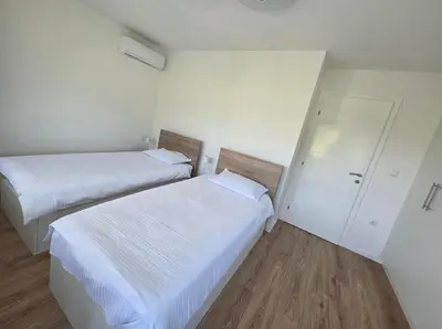 two beds in a room with white walls and wooden floors at Villa Alisa in Bihać
