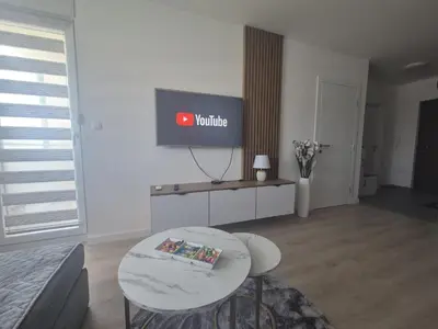 a living room with a table and a tv on the wall at Apartman Centar 8 Doboj in Doboj