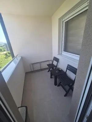 two chairs and a table in a room with a window at Apartman Centar 8 Doboj in Doboj