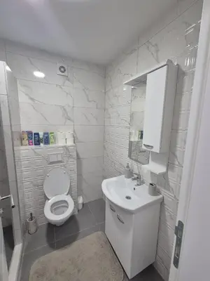 a white bathroom with a toilet and a sink at Apartman Centar 8 Doboj in Doboj
