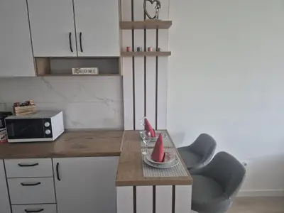 a kitchen with a counter with a table and a chair at Apartman Centar 8 Doboj in Doboj