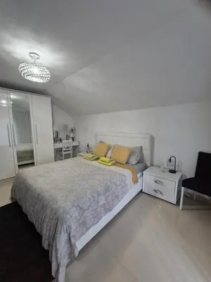 a bedroom with a large bed and a chair at Apartman IN in Bihać