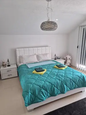 a bedroom with a large bed with a blue comforter at Apartman IN in Bihać