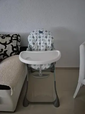 a white high chair sitting next to a bed at Apartman IN in Bihać