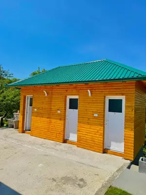 a wooden building with three doors and a green roof at Nedzad Barrel Apartments in Visoko