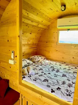 a bed in a wooden cabin with a window at Nedzad Barrel Apartments in Visoko
