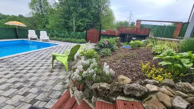 a backyard with a swimming pool and a garden with plants at Vikendica Mala Priča in Srebrenik