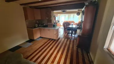 a kitchen and dining room with a wooden floor at Vikendica Mala Priča in Srebrenik