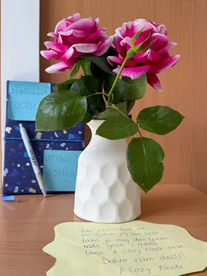 a vase with pink flowers on a table with a note at A Cozy Nest in Teslic in Teslić