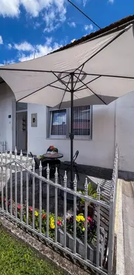 a fence with an umbrella in front of a house at A Cozy Nest in Teslic in Teslić