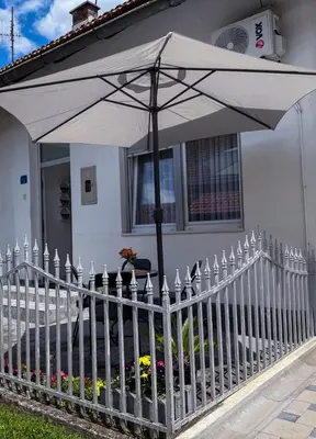 a white fence with an umbrella in front of a house at A Cozy Nest in Teslic in Teslić